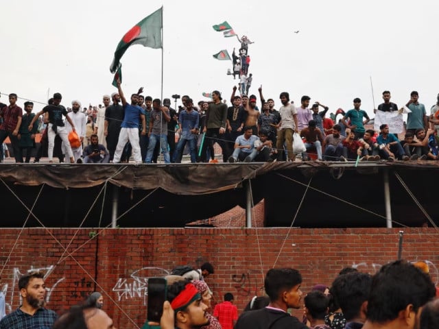 people waves bangladeshi flags on top of the ganabhaban the prime minister s residence as they celebrate the resignation of pm sheikh hasina in dhaka bangladesh august 5 2024 photo reuters